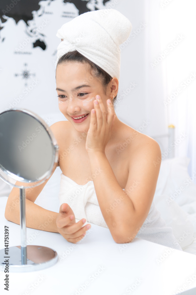 Asian young woman with towel wrapped on head and body applying makeup after shower, Morning beauty routine before work Asian young woman with towel wrapped on head and body applying makeup after shower, Morning beauty routine before work