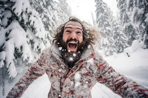 Happy hiker with long hair and beard enjoying snowfall in snowy forest during winter