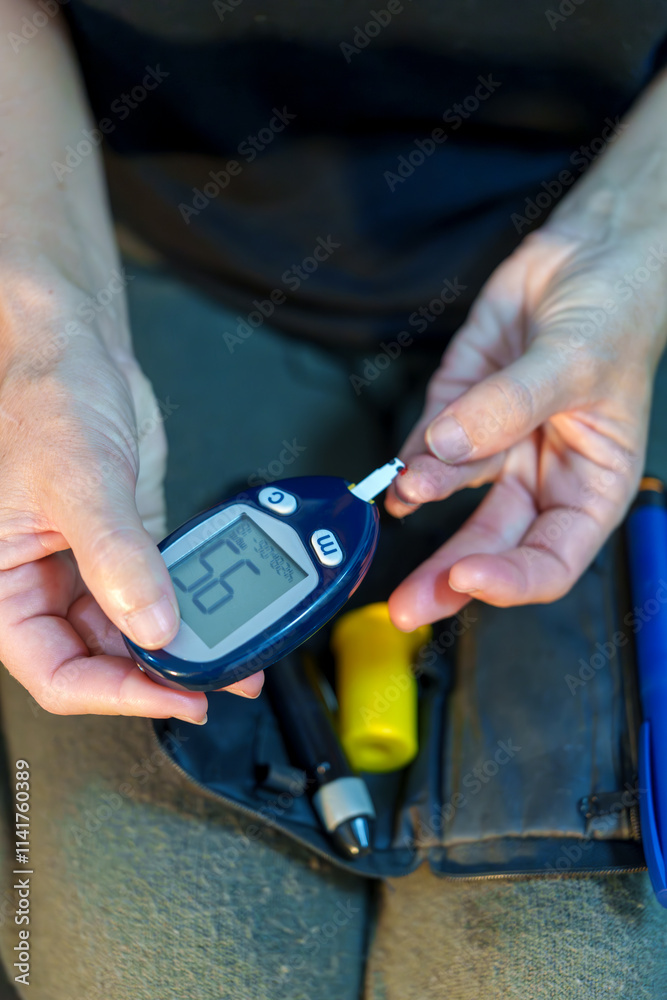 Woman using a portable glucometer to check her blood glucose at home by pricking her finger Woman using a portable glucometer to check her blood glucose at home by pricking her finger
