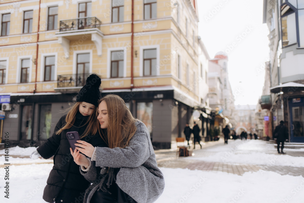 A mother and daughter take a selfie on the street in a winter city A mother and daughter take a selfie on the street in a winter city