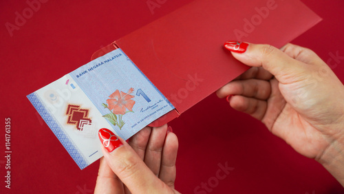 Cuadro en lienzo An unlucky Malaysian chinese woman opening a red envelope gift, only to find a very small amount of money inside, one ringgit