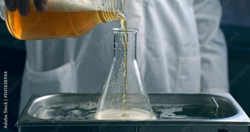 Super slow motion of lab worker pours beer into glassware for quality testing, ensuring it meets production standards. The beer is carefully inspected in brewery with precision and dedication.