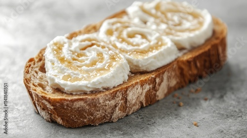 Baguette slice topped with creamy swirl cheese and honey for a delectable breakfast or snack on textured background