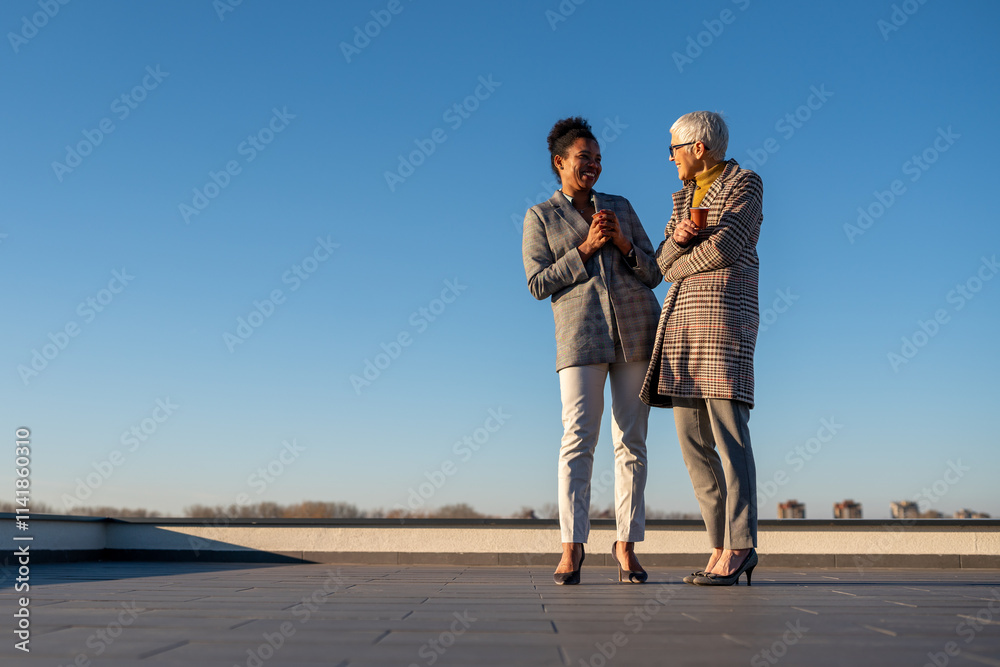 Two diverse business woman holding cup of coffee outdoors. Business woman talking for business plan Two diverse business woman holding cup of coffee outdoors. Business woman talking for business plan