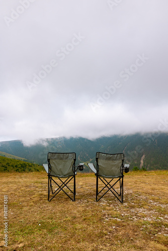 Two camping charis and misty mountains on the background photo