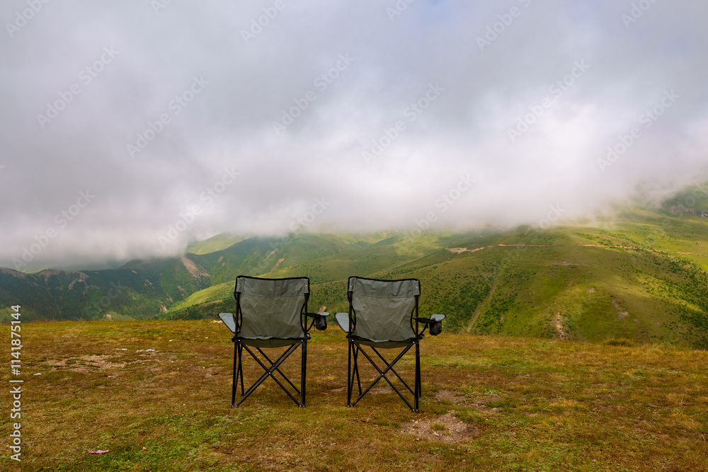 Camping chairs and landscape of the mountains with clouds on the background Camping chairs and landscape of the mountains with clouds on the background