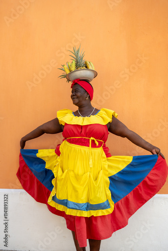 A Palenquera Woman Wearing A Red, Yellow, And Blue Dress, Holding Out Her Skirt With A Fruit Basket Balanced On Her Head