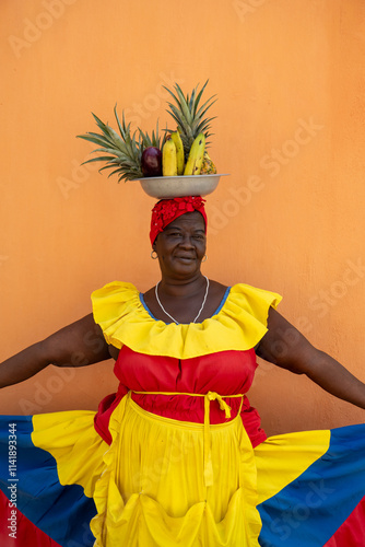 A Palenquera Woman Wearing A Red, Yellow, And Blue Dress, Holding Out Her Skirt With A Fruit Basket Balanced On Her Head