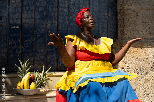 Colombian Woman In Traditional Dress Sitting On Stairs With A Bowl Of Tropical Fruits