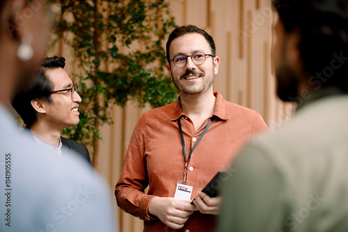 Smiling male entrepreneur discussing with delegates in seminar at convention center