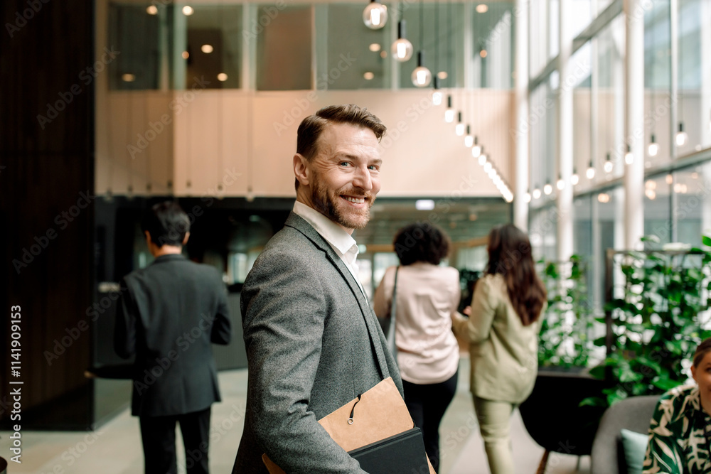 Side view portrait of smiling male entrepreneur in lobby at convention center Side view portrait of smiling male entrepreneur in lobby at convention center