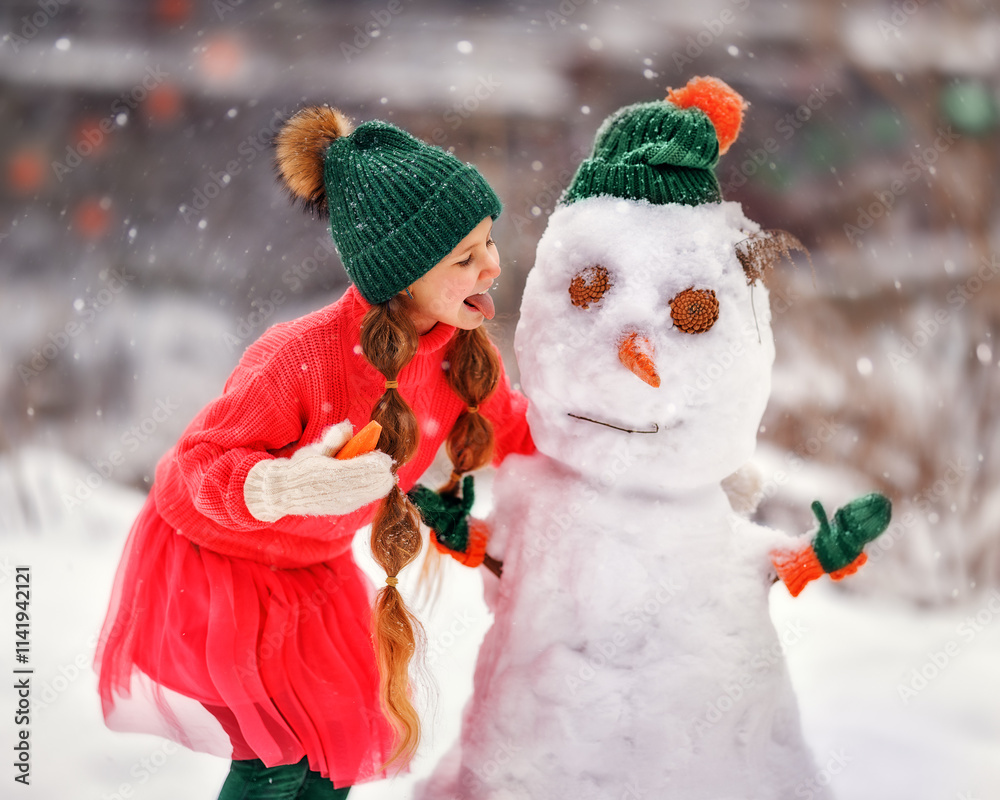 Kid girl makes snowman on winter frosty day. Child makes nose out of carrot. Outdoor family fun on Christmas vacation in the winter new year