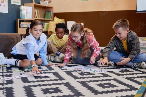 Full length of multiethnic group of children learning English alphabet and playing with letter cards sitting on floor in school classroom together