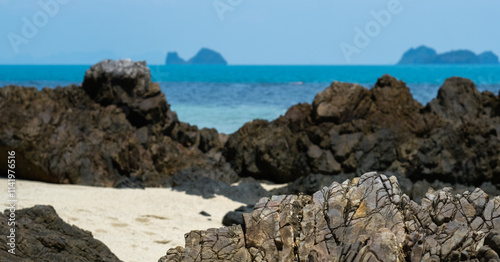 A rocky beach on Koh Samui, Thailand, featuring rugged volcanic rocks, soft sand, and a turquoise sea.