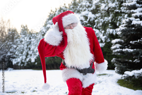 Santa Claus for the New Year and Christmas goes listening, holding his hand to his ear in a red hat and costume