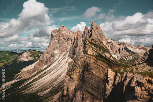 Massif montagneux imposant avec crêtes rocheuses et vallées verdoyantes sous un ciel nuageux photo