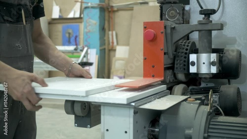 automated woodworking process, worker puts chipboard detail in edge banding machine, closeup