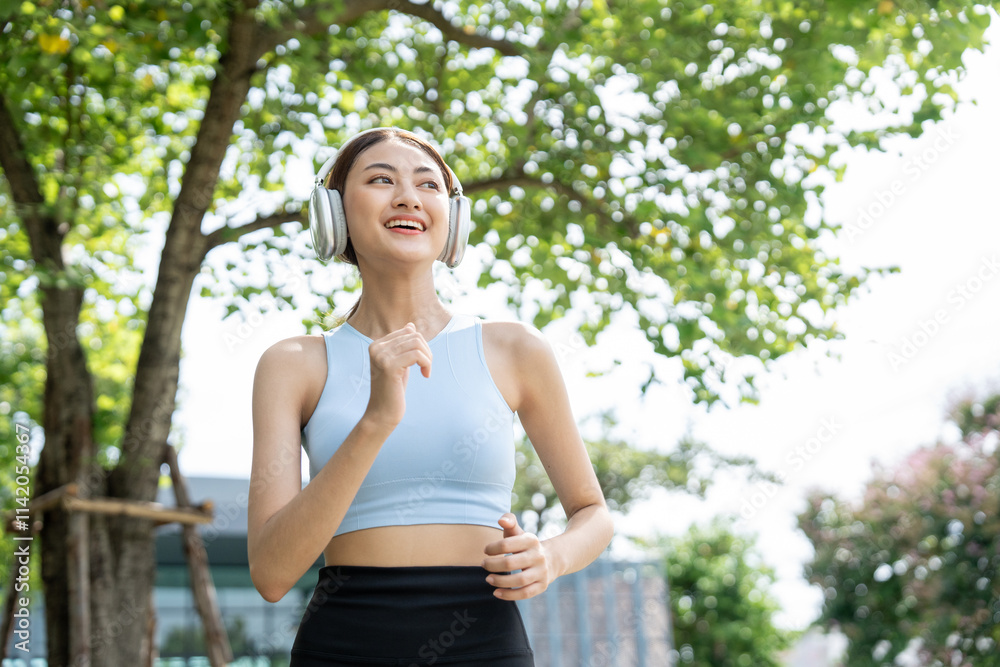Happy slim beautiful woman wearing sportswear jogging in the park with sunrise. Young beautiful asian female in sportswear running outdoor. Workout exercise in the morning listen music with headphone Happy slim beautiful woman wearing sportswear jogging in the park with sunrise. Young beautiful asian female in sportswear running outdoor. Workout exercise in the morning listen music with headphone