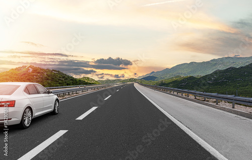Obraz na płótnie The car is driving along the highway surrounded by picturesque nature. w salonie