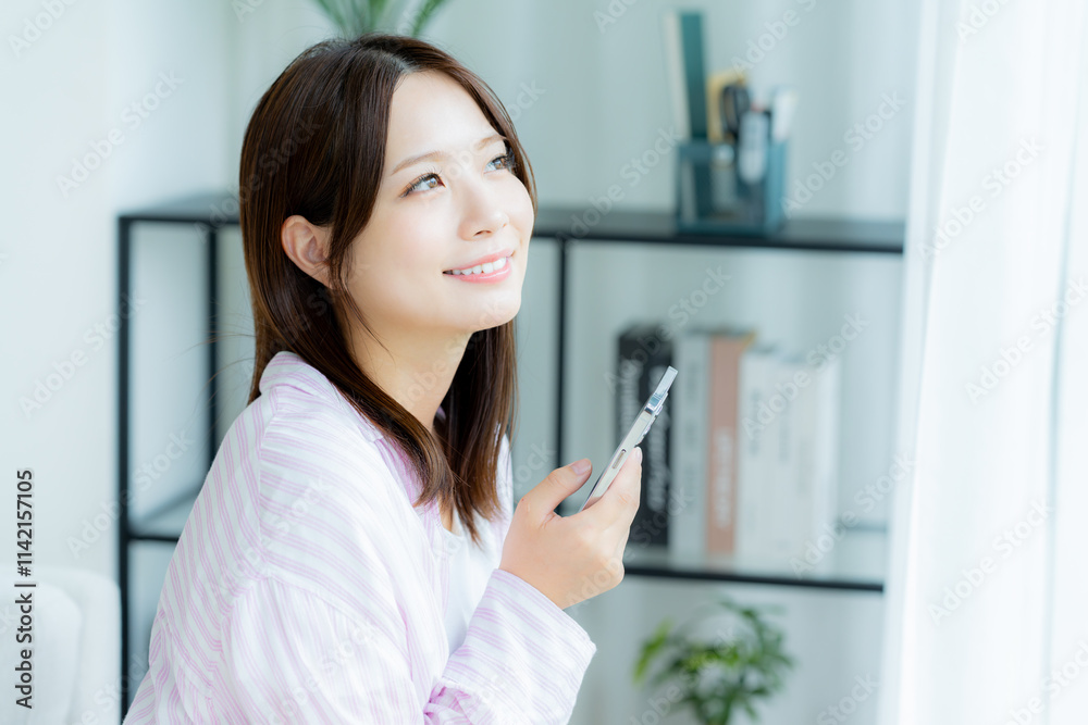 部屋でスマホを操作する若い女性 部屋でスマホを操作する若い女性