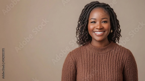 Female model in cozy autumn sweater dress, smiling warmly in front of soft studio backdrop, photo