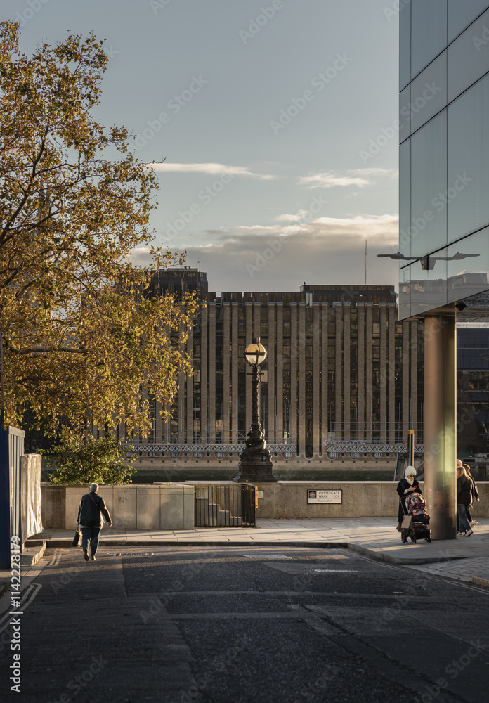 People and Tourists walk through on Thames Path at Oystergate Walk with Minerva House in the background at London. Space for text, Selective Focus.