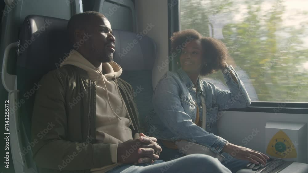 Passengers, a young African American woman, and a man having a friendly conversation during a train travel around Europe, handheld shot.