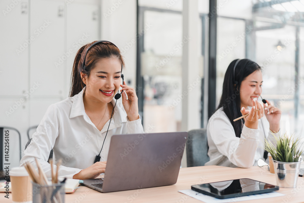 Two women working in modern office with headsets and laptops Two women working in modern office with headsets and laptops