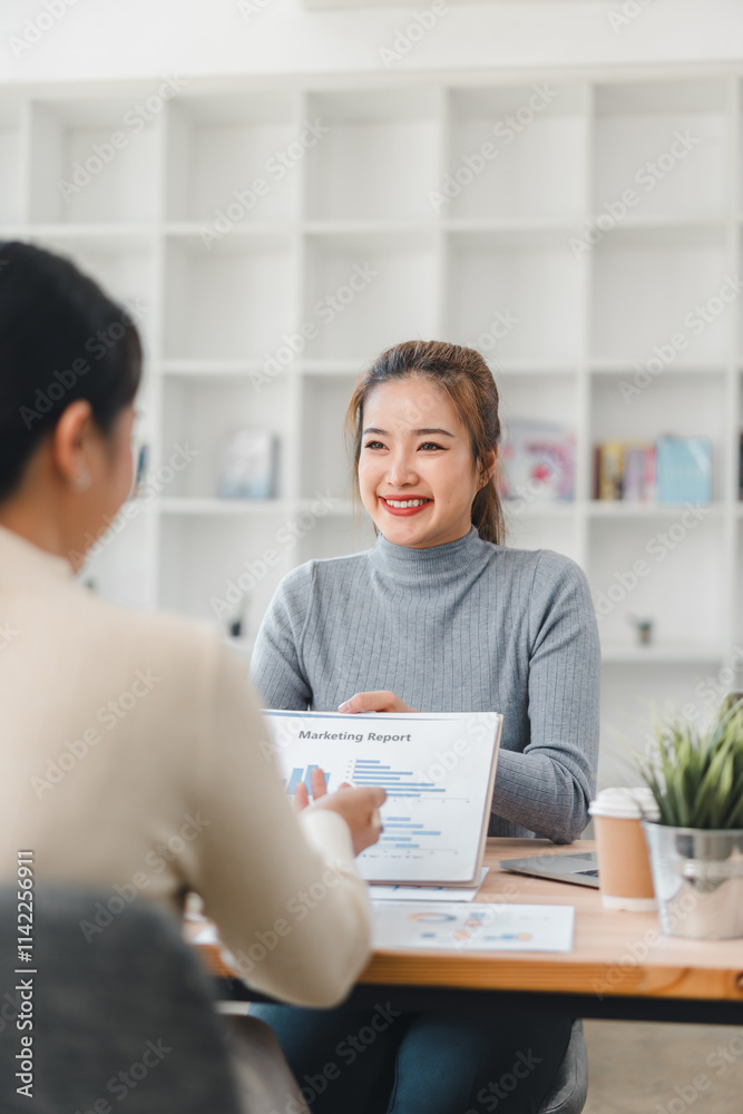 Two women discussing marketing report in modern office Two women discussing marketing report in modern office
