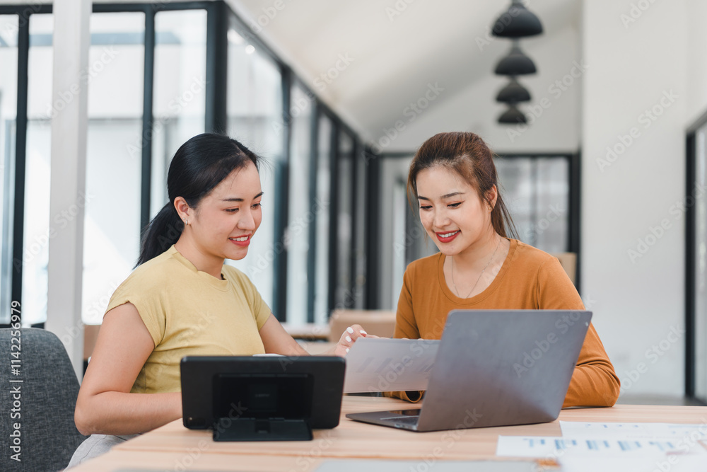 Two women collaborating at modern office desk with devices Two women collaborating at modern office desk with devices
