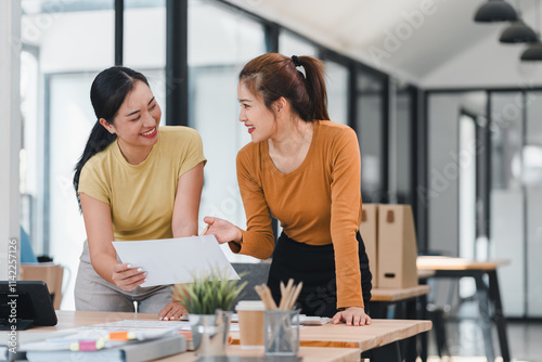 Two women collaborating in modern office with smiles