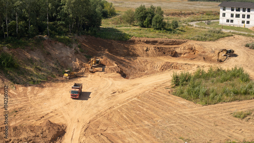 yellow excavator, yellow bulldozer and red dump truck on a construction site, top view, start of construction, preparation of construction site