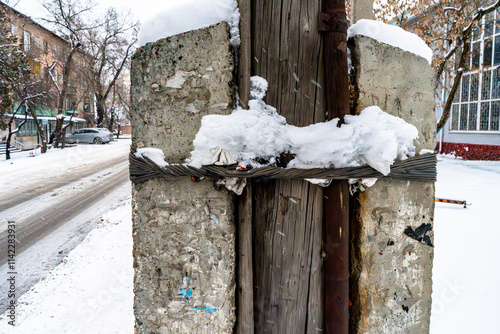 Εκτύπωση καμβά A snow-covered urban utility post made of weathered concrete, wooden planks, and old metal wiring