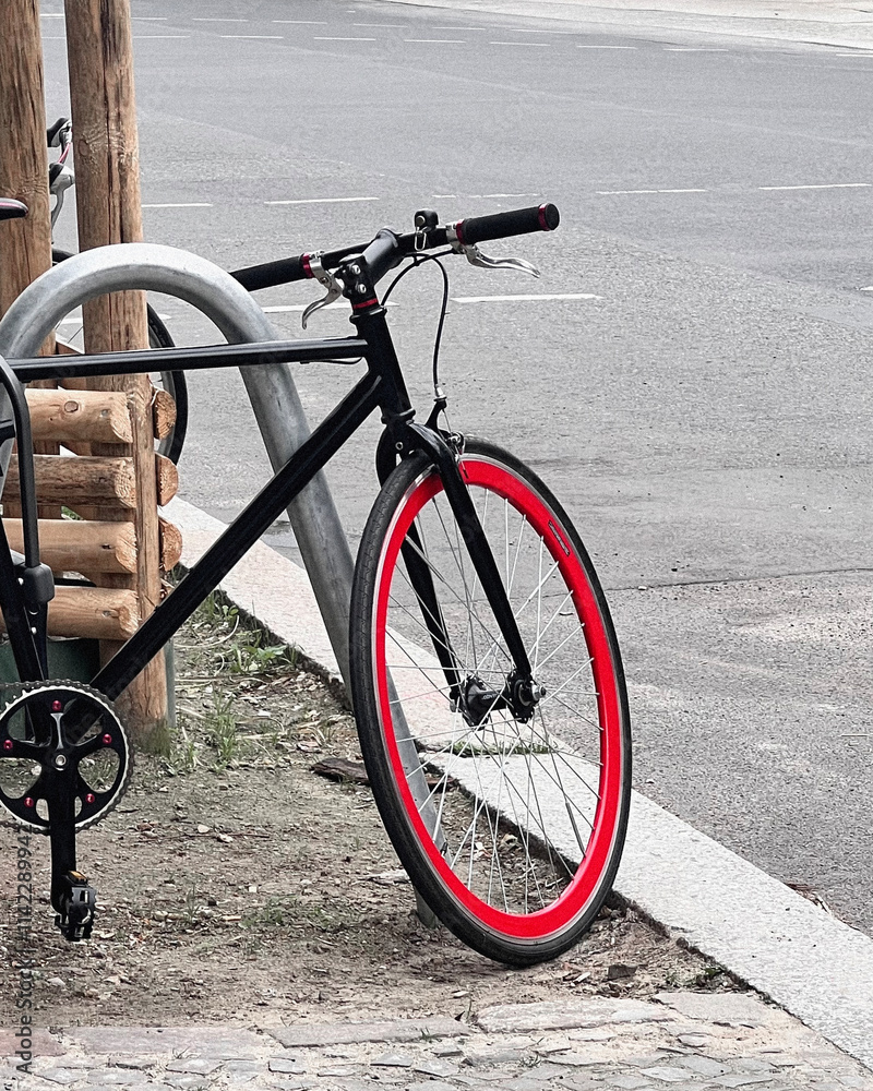 Modern Black Bicycle with Red Rim Parked on Street in Berlin, Germany Modern Black Bicycle with Red Rim Parked on Street in Berlin, Germany