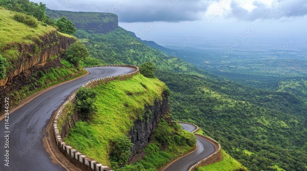 Fototapeta premium Scenic Winding Road Through Lush Green Mountains Under Cloudy Sky