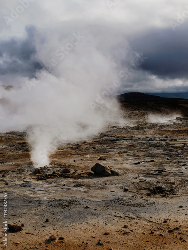 Steaming geothermal landscape under dramatic cloudy skies in Iceland