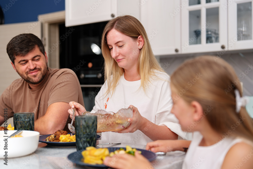 A woman serves food to her family in a kitchen A woman serves food to her family in a kitchen