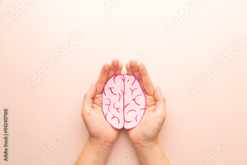 Woman hands holding human brain shape made from paper on beige background. Awareness of Alzheimer, Parkinson's disease, dementia, stroke, seizure or mental health. Neurology and Psychology care.