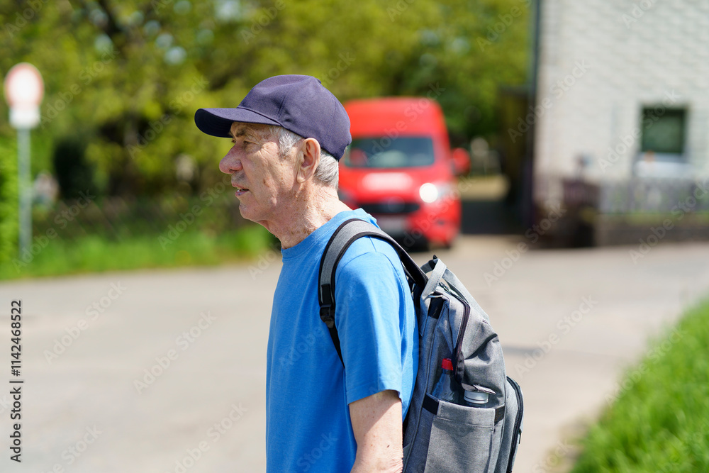 Obraz premium Elderly man with a backpack on his shoulder walking along the street