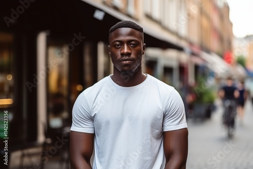 A man wearing a white shirt stands in front of a building