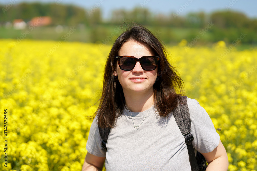 Young woman in sunglasses standing in a field of blooming rapeseed Young woman in sunglasses standing in a field of blooming rapeseed