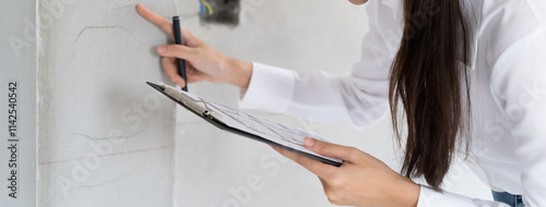 Asian inspector checking structure of new property and taking note in the clipboard for review and fix the house before sell to client