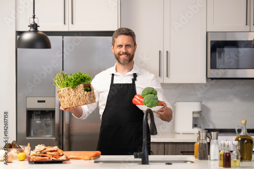 Home menu with fresh food ingredient. Man cook cooking at kitchen. Hispanic man standing in kitchen preparing food. Millennial man cook healthy salad. Food diet. Man cook a tasty meal photo