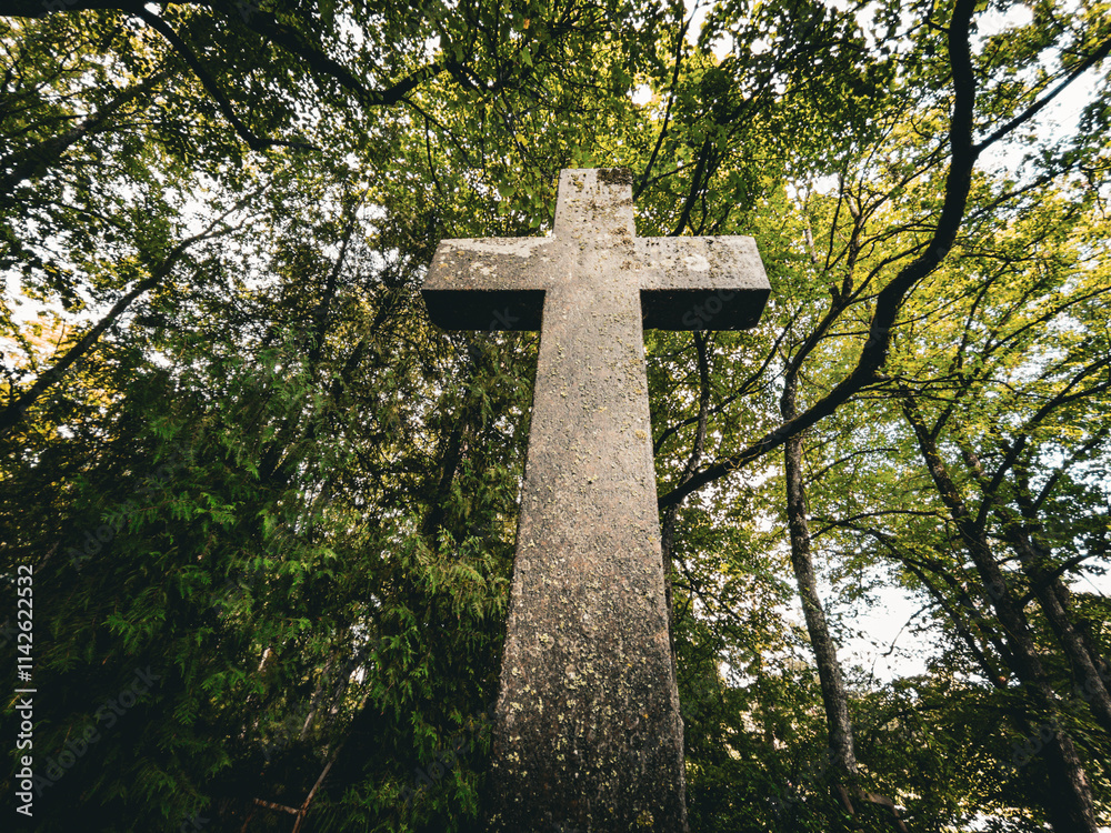 A weathered stone cross stands among vibrant trees, evoking tranquility and deep peaceful reflection A weathered stone cross stands among vibrant trees, evoking tranquility and deep peaceful reflection
