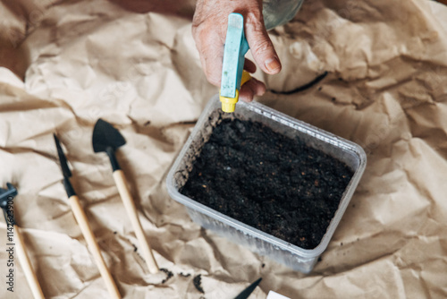 Kraft paper background, fertile soil and garden tools on top, top view. Planting seedlings in spring