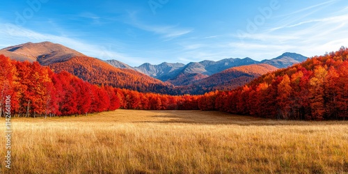 Valley meadow geography concept. Vibrant autumn landscape with colorful trees, grassy field, and mountains under a clear blue sky.