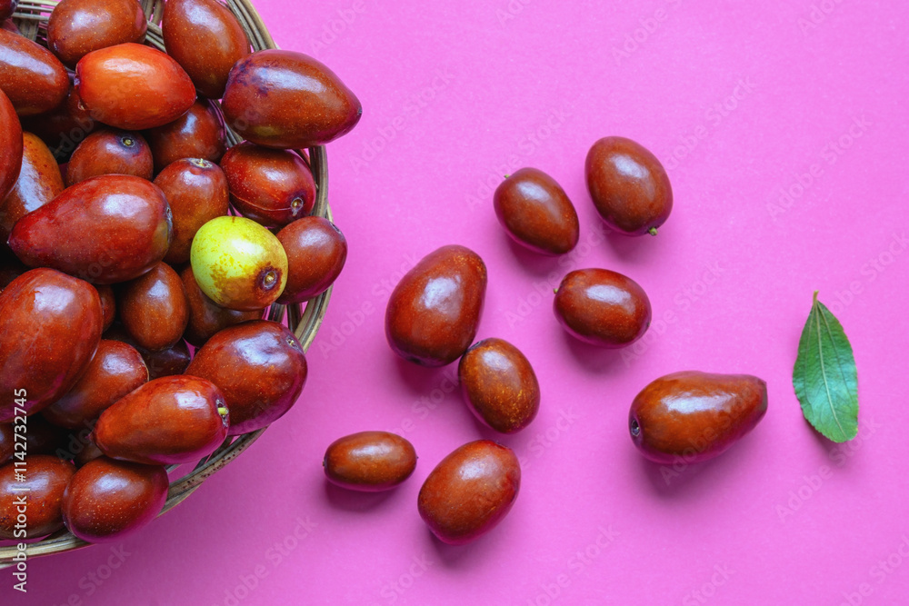 Jujube fruit ( Ziziphus jujuba ) in small basket on pink background. Copy space Jujube fruit ( Ziziphus jujuba ) in small basket on pink background. Copy space