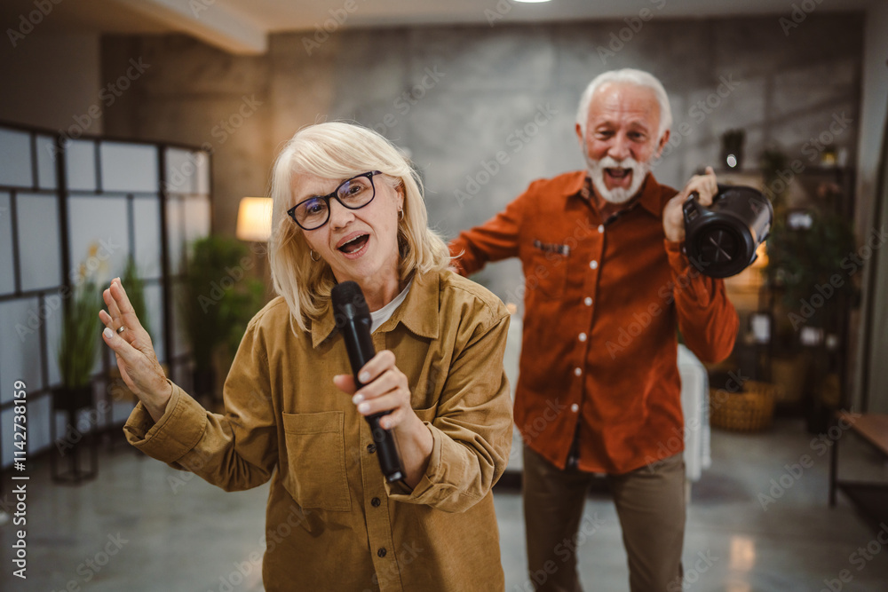 Fototapeta premium senior woman sing karaoke on microphone with senior man behind her