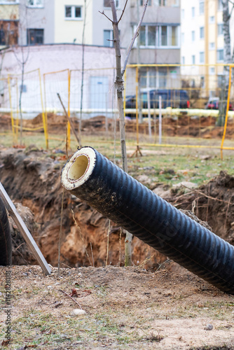 A large grouping of pipes is currently laying in the dirt within a trench photo