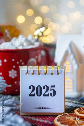 New Year 2025, tea with orange, coffee with marshmallows, books and fir branches, New Year's toys and a ball on the table.